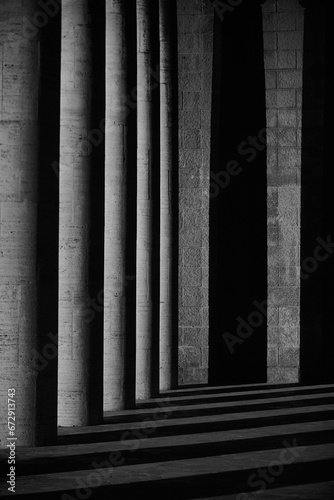 Black and white shot of a line of majestic stone pillars standing tall in an outdoor location