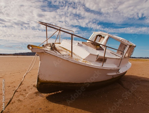 a white boat with the bow sitting on the shore of a beach