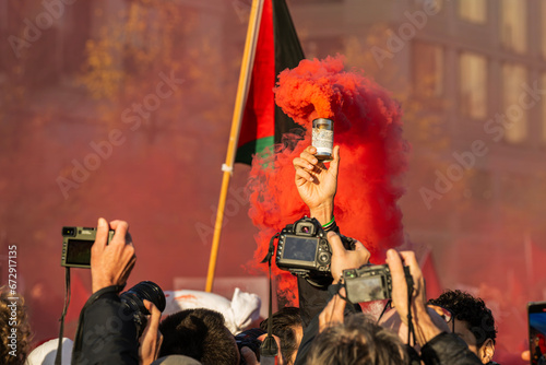 Fotografen drängen sich um einen Demonstranten der eine Rauchbombe gezündet hat photo