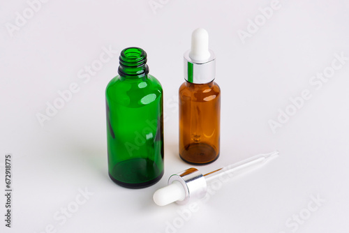 Colored glass cosmetic bottle of essential oil with dropper or pipette isolated on white background. Round bottle with DropperStop.
