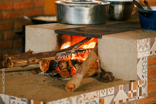 Traditional wood-fired stove cooking pots, with vibrant flames and rustic tile decor in a country kitchen