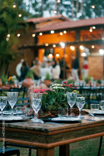 outdoor dining, sophisticated event, crystal glassware, polished plates, rustic centerpiece, wooden decor, potted herbs, table setup, celebration, elegant