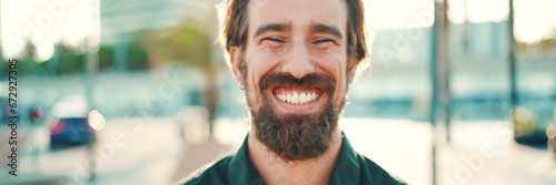 Closeup portrait of smiling man with a beard on an urban city background. Frontal close-up of happy young hipster male looking at camera © Andrii Nekrasov