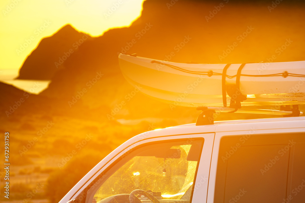 Fototapeta premium Canoe on roof top of car van at sunset