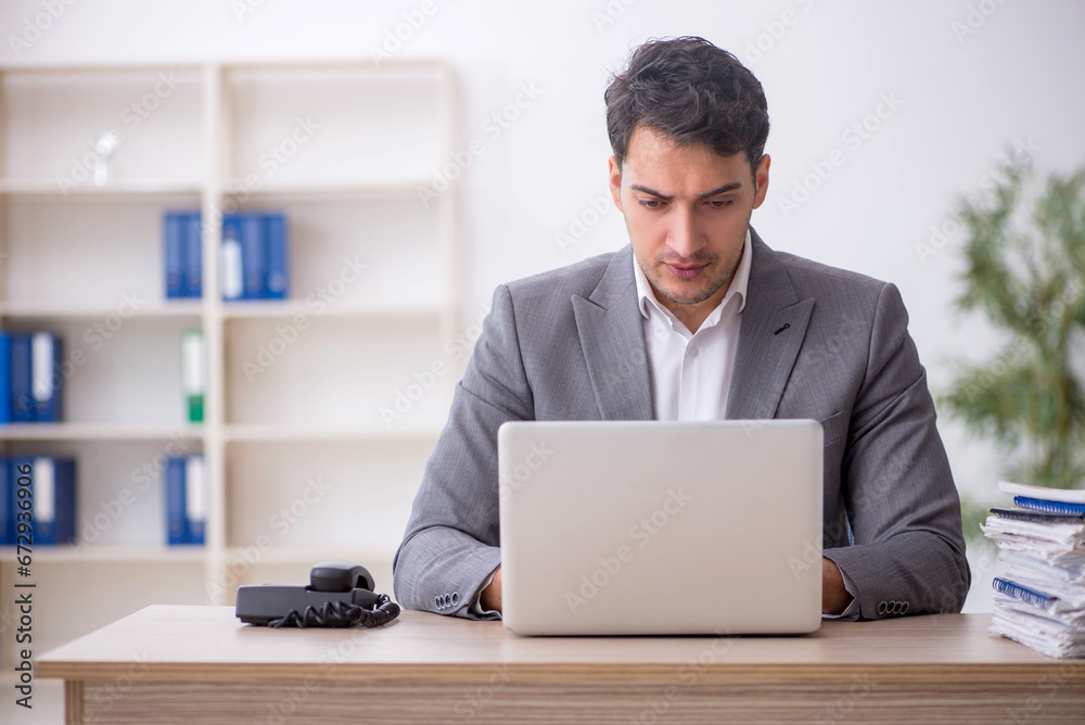 Young male employee and too much work in the office Young male employee and too much work in the office