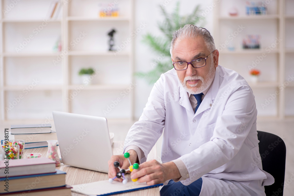 Old male doctor holding molecular model