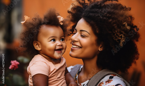 Smiling Baby Girl Receiving a Kiss from Her Black Mother photo