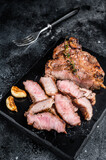 Grilled sliced pork loin steak on marble board. Black background. Top view