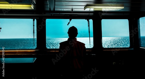 Silhouette of the captain standing near the window on a ship, taking in the view as the vessel sails photo