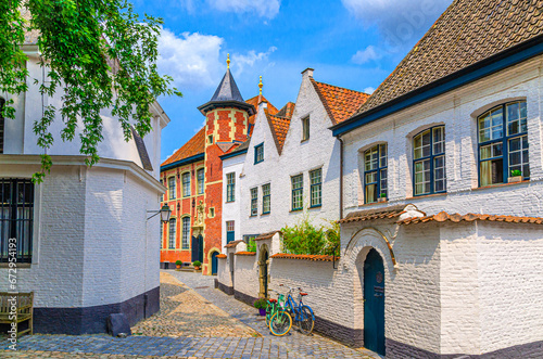 Beguinage Courtrai of Saint-Elisabeth, Begijnhof van Kortrijk with white houses and Sint-Annazaal museum, bicycles near wall on narrow cobblestone street in Kortrijk city historical centre, Belgium photo