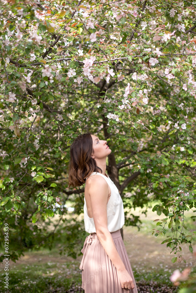 Young beautiful girl walking among plants and flowers. Ecology and eco-friendly concept Young beautiful girl walking among plants and flowers. Ecology and eco-friendly concept