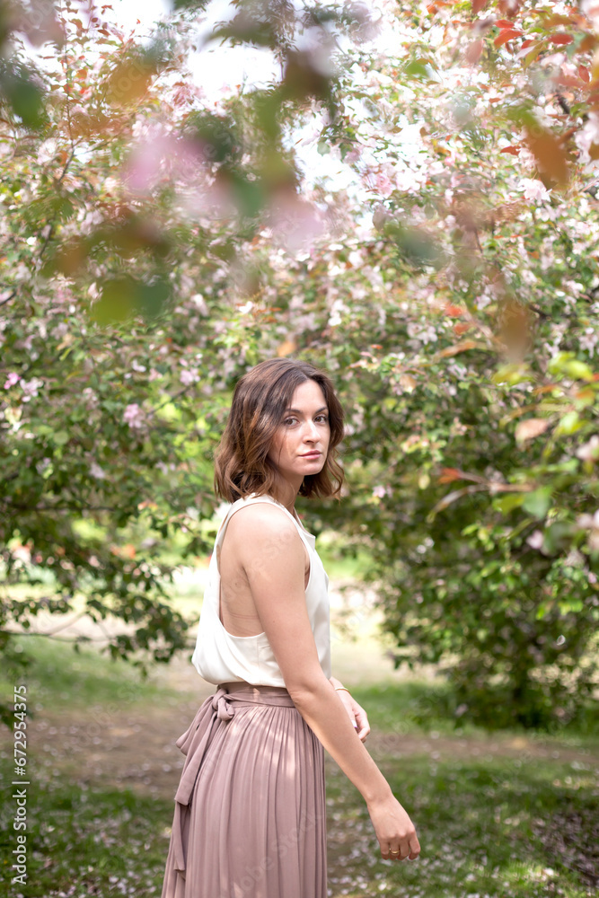 Young beautiful girl walking among plants and flowers. Ecology and eco-friendly concept Young beautiful girl walking among plants and flowers. Ecology and eco-friendly concept
