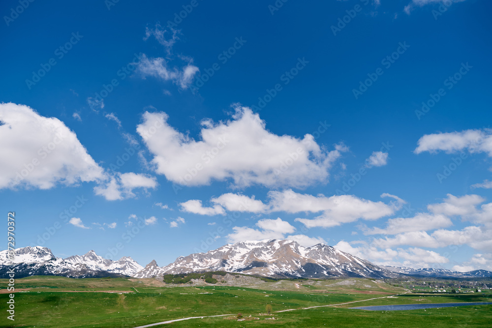 Green valley with a lake against the backdrop of snowy mountains. Durmitor, Montenegro