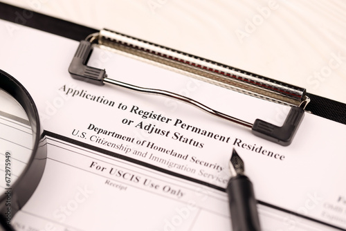 I-485 Application to register permanent residence or adjust status blank, form on A4 tablet lies on office table with pen and magnifying glass close up photo