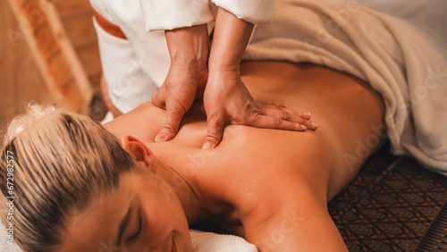 Photography Beautiful caucasian woman having back massage in front of wooden sauna cabinet