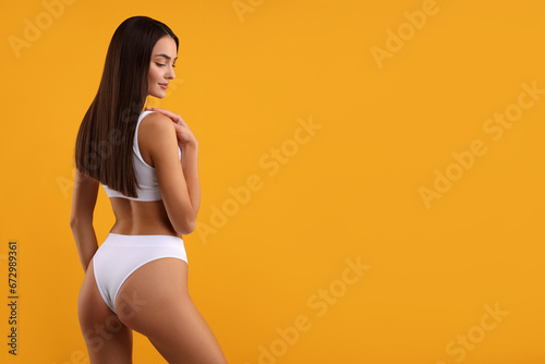 Young woman in stylish white bikini on orange background. Space for text