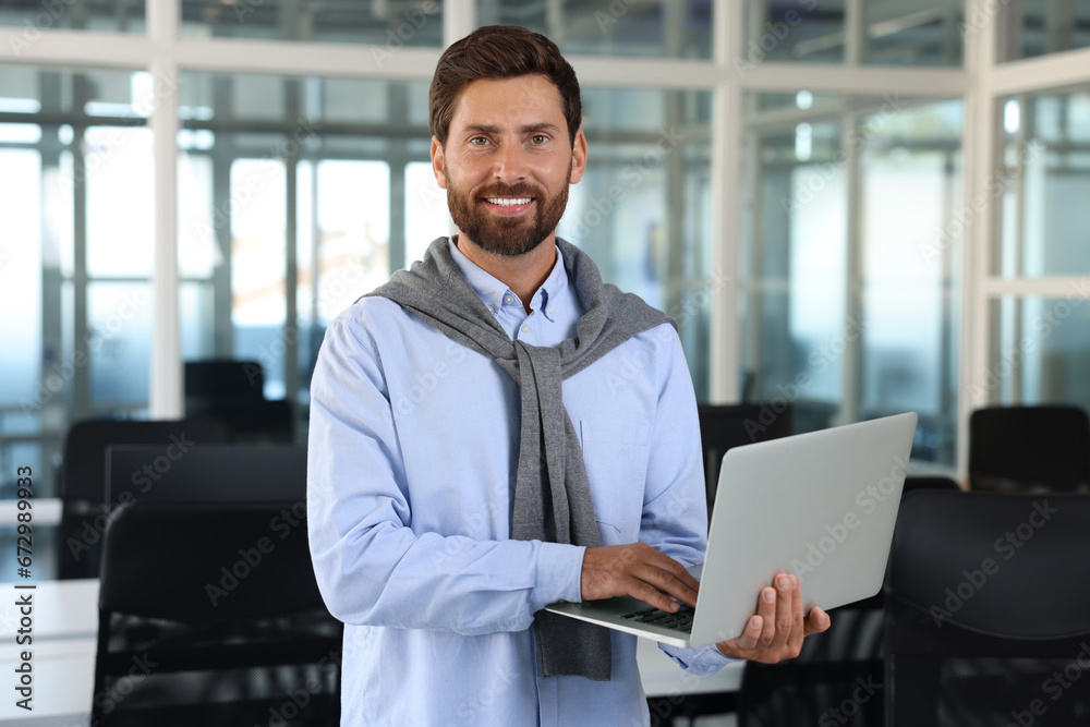Handsome happy man using laptop in office Handsome happy man using laptop in office