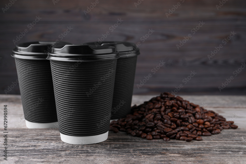 Coffee to go. Paper cups and roasted beans on wooden table. Space for text Coffee to go. Paper cups and roasted beans on wooden table. Space for text