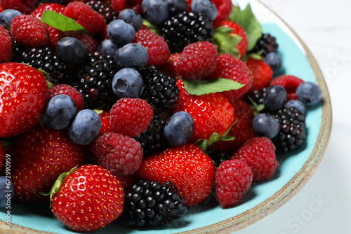 Many different fresh ripe berries in bowl on white table  closeup