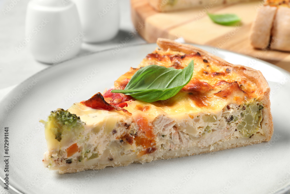 Tasty quiche with chicken, vegetables, basil and cheese on light table, closeup Tasty quiche with chicken, vegetables, basil and cheese on light table, closeup