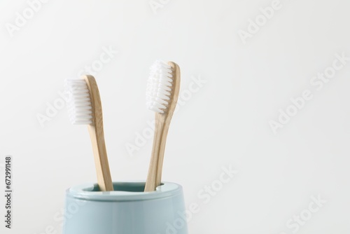 Bamboo toothbrushes in holder on white background  closeup. Space for text