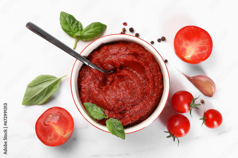 Tasty tomato paste in bowl and ingredients on white table, flat lay Tasty tomato paste in bowl and ingredients on white table, flat lay