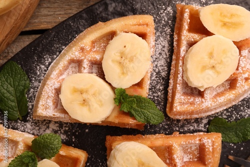 Tasty Belgian waffles with banana and mint on table, top view