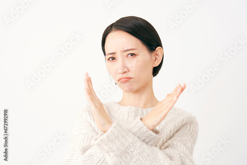 腕でばつ印のジェスチャーをする中年女性　白背景