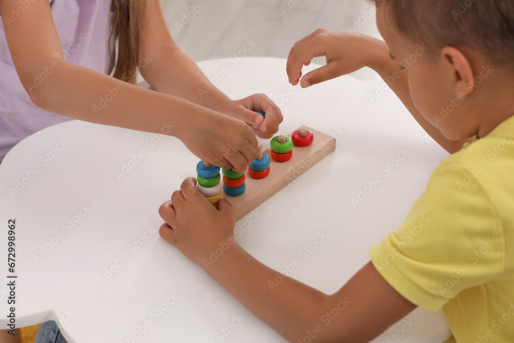 Little children playing with stacking and counting game at desk, closeup. Kindergarten activities for motor skills development Little children playing with stacking and counting game at desk, closeup. Kindergarten activities for motor skills development
