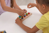 Little children playing with stacking and counting game at desk, closeup. Kindergarten activities for motor skills development