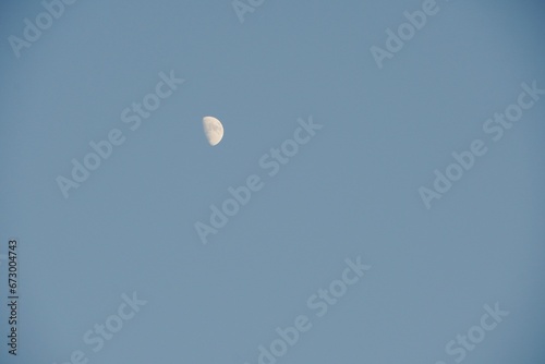 Moon in the sky. Low angle view of Moon isolated in the clear blue sky background at evening sunset.