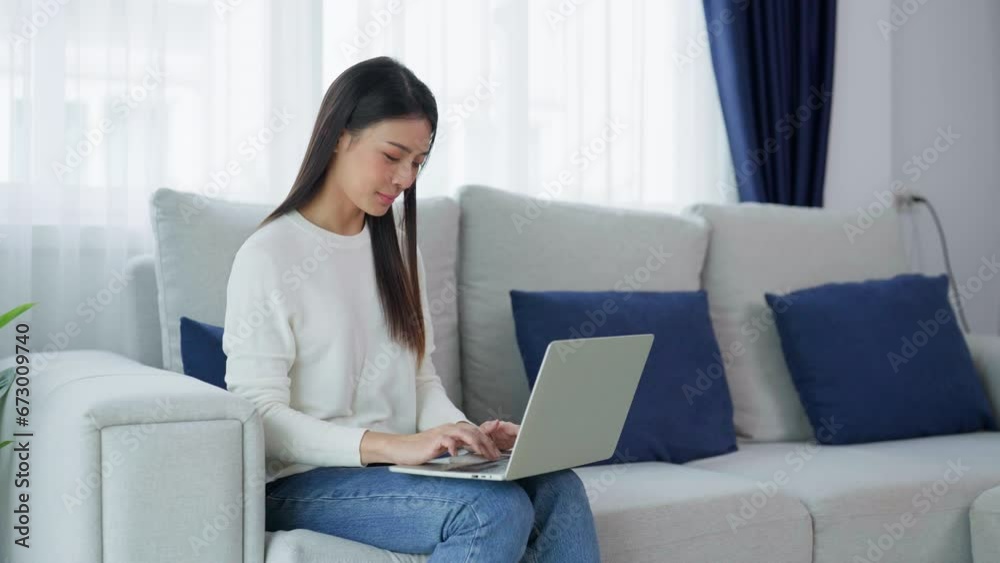 Young asian woman using laptop while seated on couch at home Young asian woman using laptop while seated on couch at home