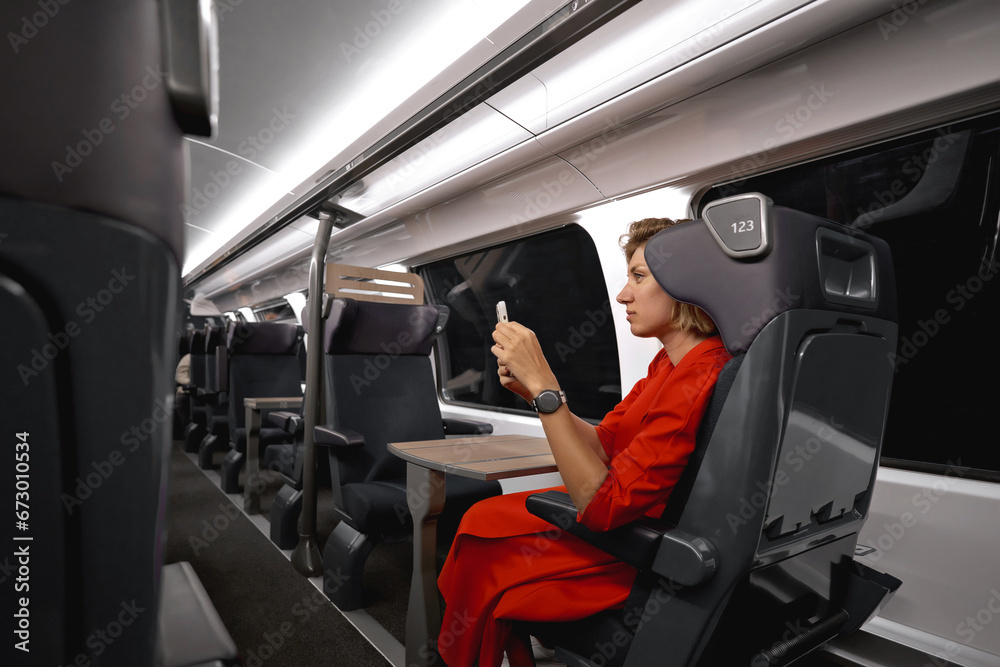 Businesswoman with ginger hair on train traveling to another city for an important meeting. Woman traveling with social distance for pandemic protection enjoying 5g mobile connection in train wagon. Businesswoman with ginger hair on train traveling to another city for an important meeting. Woman traveling with social distance for pandemic protection enjoying 5g mobile connection in train wagon.