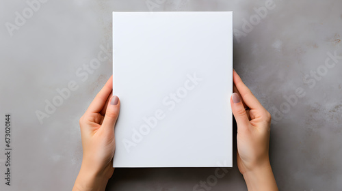 Mockup design template with a blank magazine being held by female hands against a gray background, photo