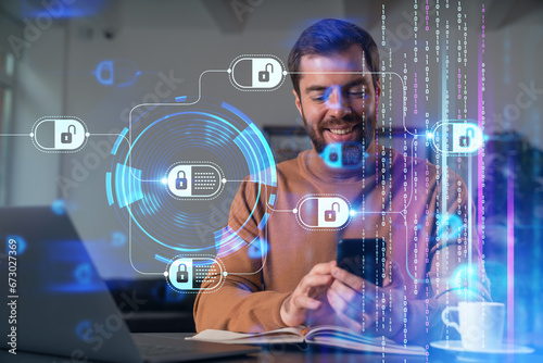 Handsome businessman working on laptop at office workplace in background. Using phone to read text, and send messages. Concept of business education, blockchain cryptocurrency technology. photo