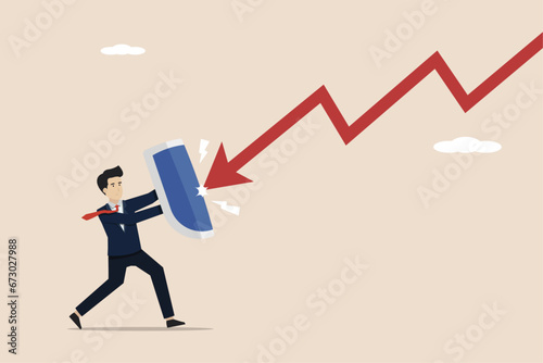 Protection or defensive stock in an economic crisis or market crash, business resilience to survive adversity, businessman holding a shield to cover and protect from the arrow of downturn. photo