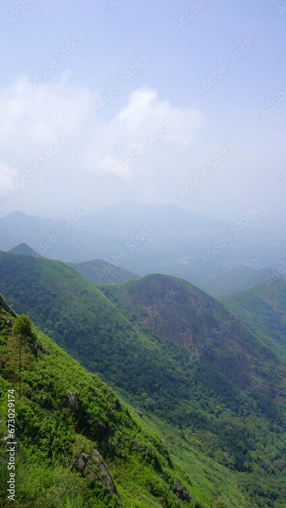 Fototapeta premium Beautiful dense green lush landscapes of kodaikanal hillstation filled with mist and cloudy sky.