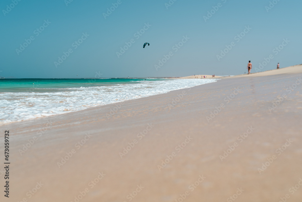 Weiter Strand mit Ocean und Kitesurfer im Hintergrund am Horizont 