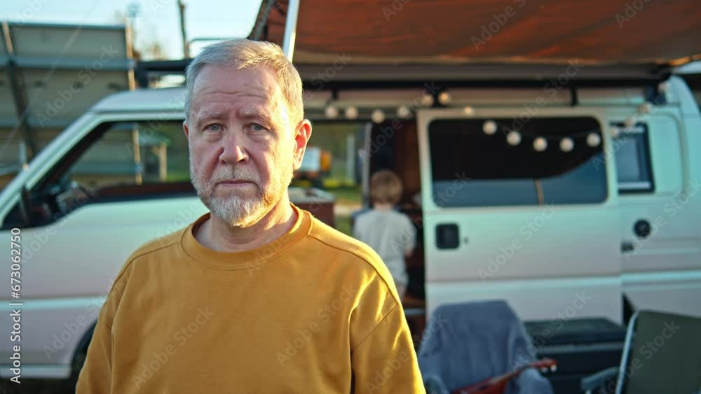 Portrait of elder man in front of custom camper van near solar panels. Happy and confident. Sunny yellow t-shirt look. Vacations Portrait of elder man in front of custom camper van near solar panels. Happy and confident. Sunny yellow t-shirt look. Vacations