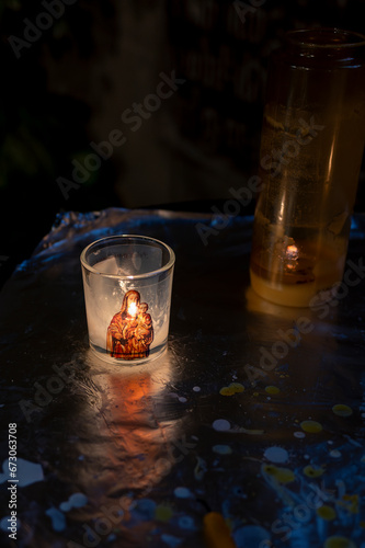 Photophore illustré de la vierge Marie brulant dans une église sombre photo