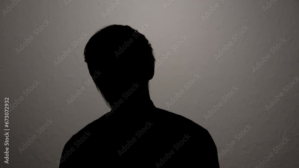 Silhouette of man hiding identity while giving anonymous interview on camera.