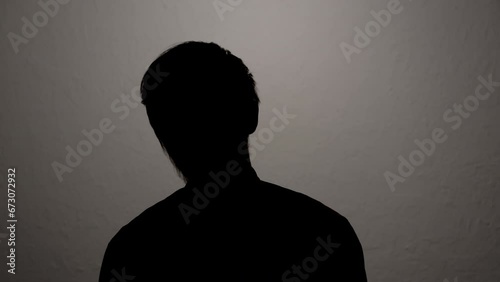 Silhouette of man hiding identity while giving anonymous interview on camera. photo