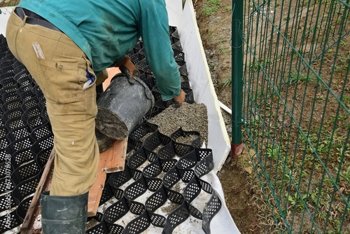 Obraz na płótnie Pouring crushed stone into the plastic net and compacting the plastic net with mesh w salonie