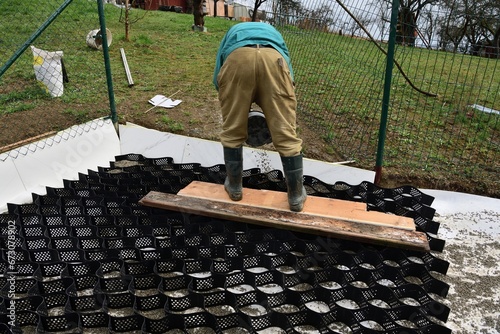 Obraz na płótnie Pouring crushed stone into the plastic net and compacting the plastic net with mesh w salonie