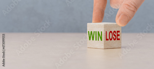 Win or lose, business concept. Businessman hand turns wooden cubes and changes word Lose to Win. Wooden cubes with win and lose text standing on table
