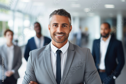 Portrait of handsome smiling businessman with his colleagues, Multi-ethnic group of business persons standing in modern office