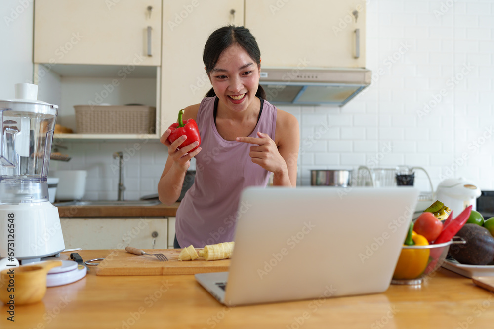 Confident young woman in exercise clothes talking Live broadcast via laptop computer presenting bell peppers that are beneficial to the skin excretory system shape proportions After exercising at home Confident young woman in exercise clothes talking Live broadcast via laptop computer presenting bell peppers that are beneficial to the skin excretory system shape proportions After exercising at home