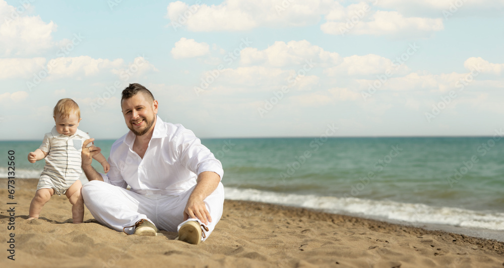 Happy father sitting on a beach with his little son