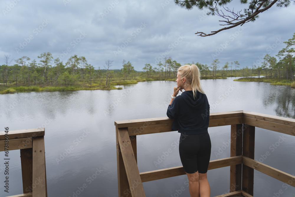 A young Estonian girl at a swimming spot in a swamp, the sky is overcast.
