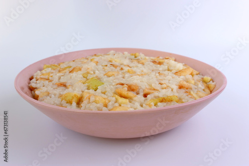 Rice porridge with apples in a pink bowl on a white background.